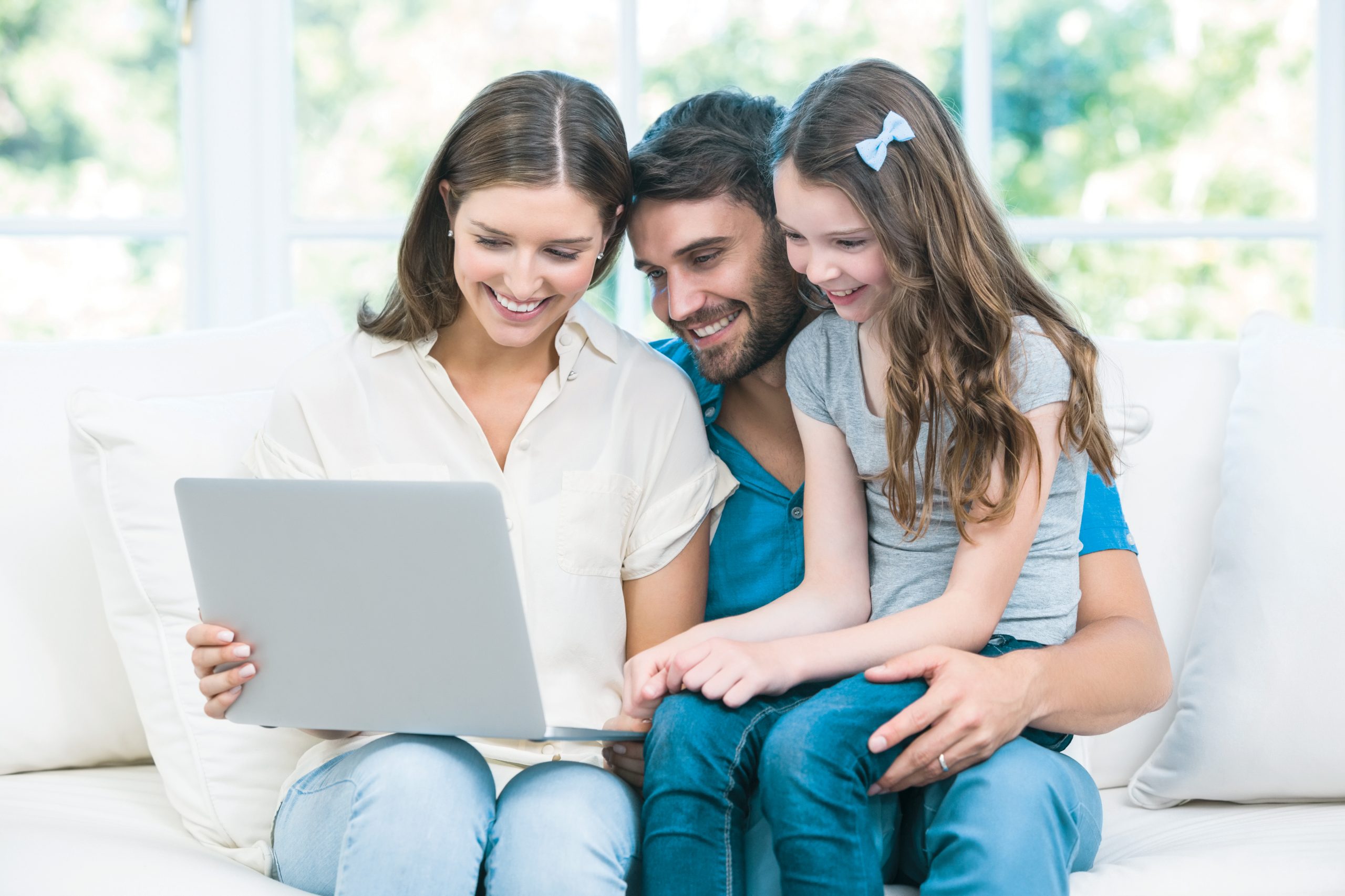 family sitting on a couch looking at a laptop computer